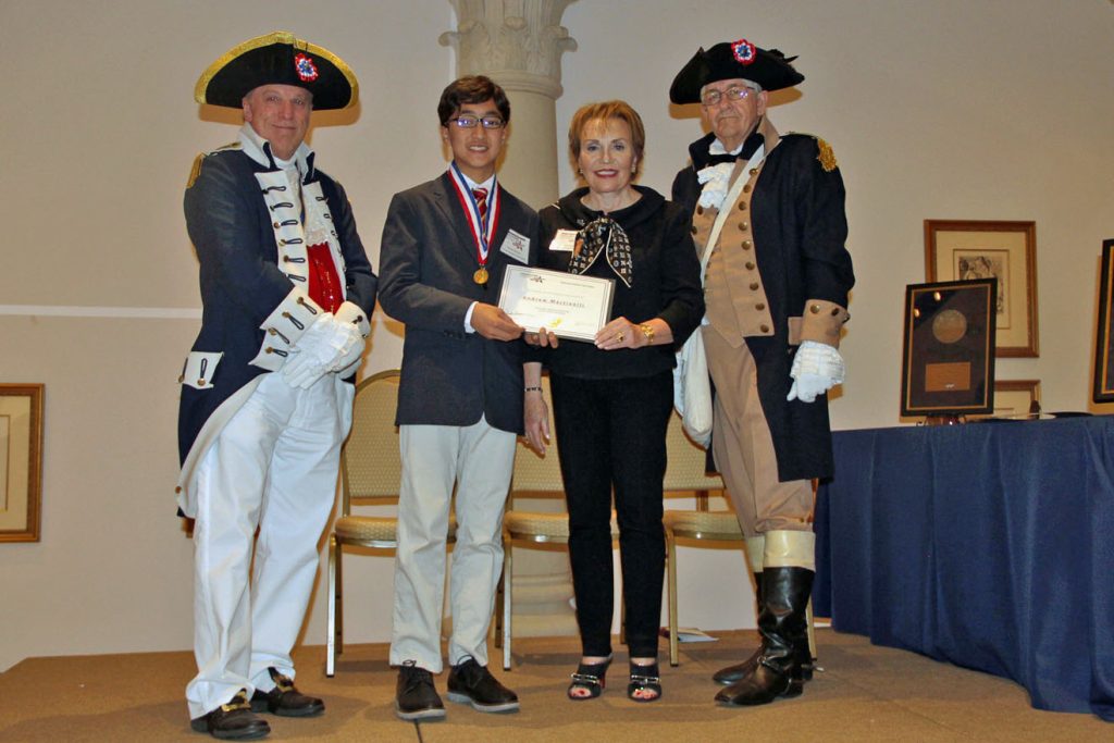 Adult and student standing next to adults dressed in historical costumes all holding award