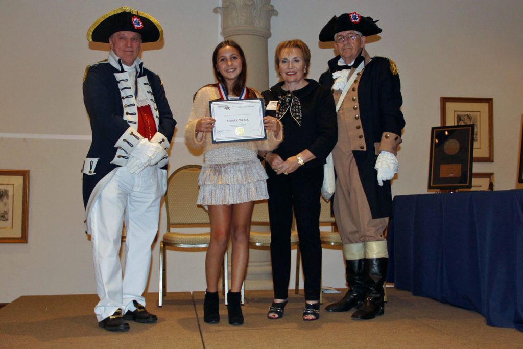 Student and adult standing next to two adults in historical costumes holding an award