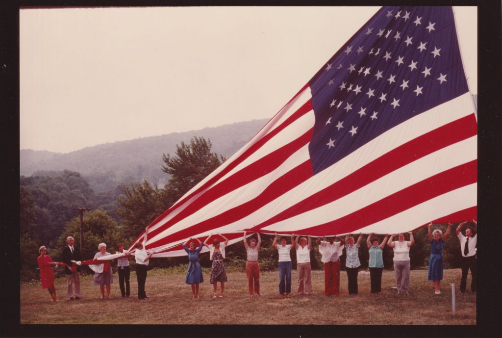 FFVF staff hold the flag on the Valley Forge campus.