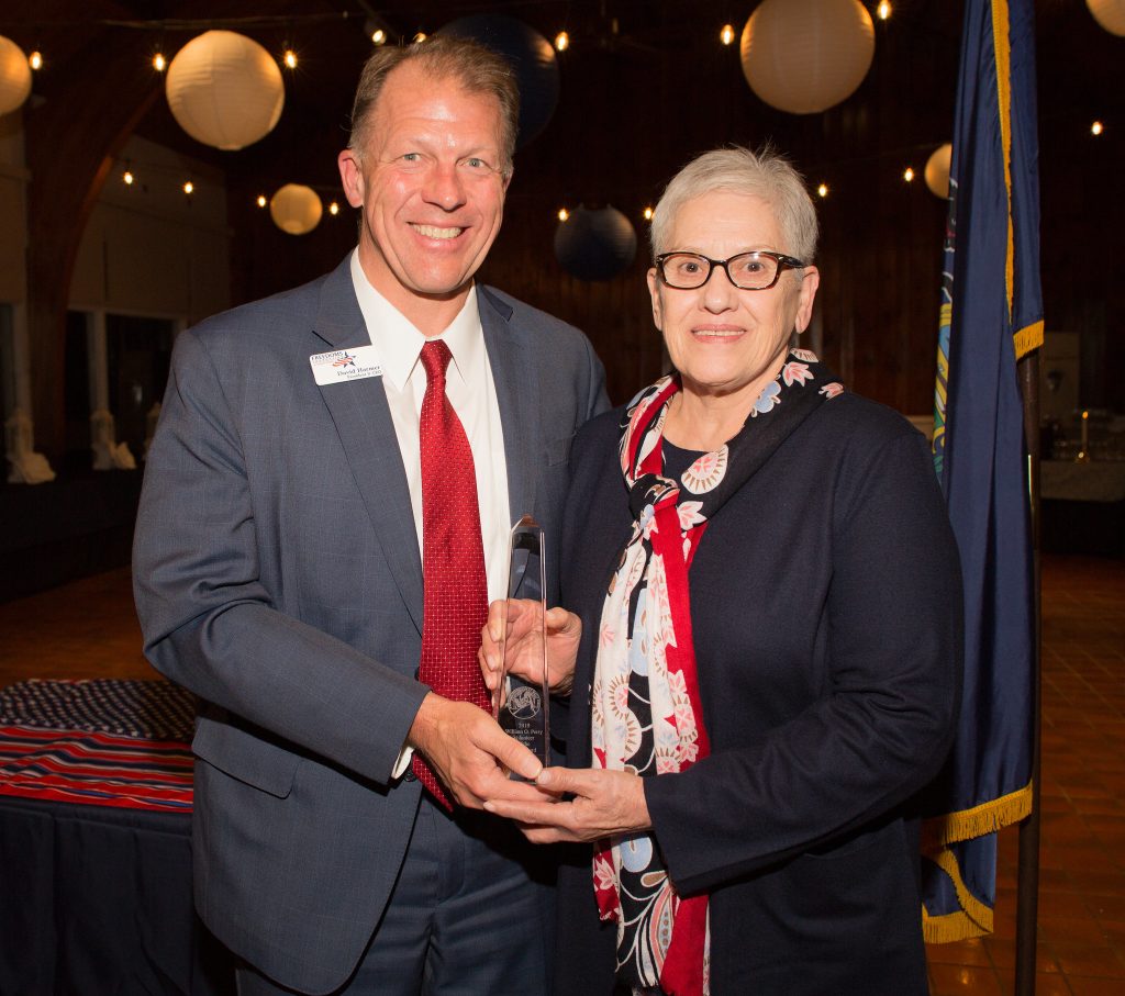 CEO David Harmer stands with Molly Wehrenburg holding a glass award.