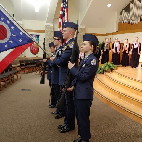 Young people in uniform holding flags as part of a ceremony.