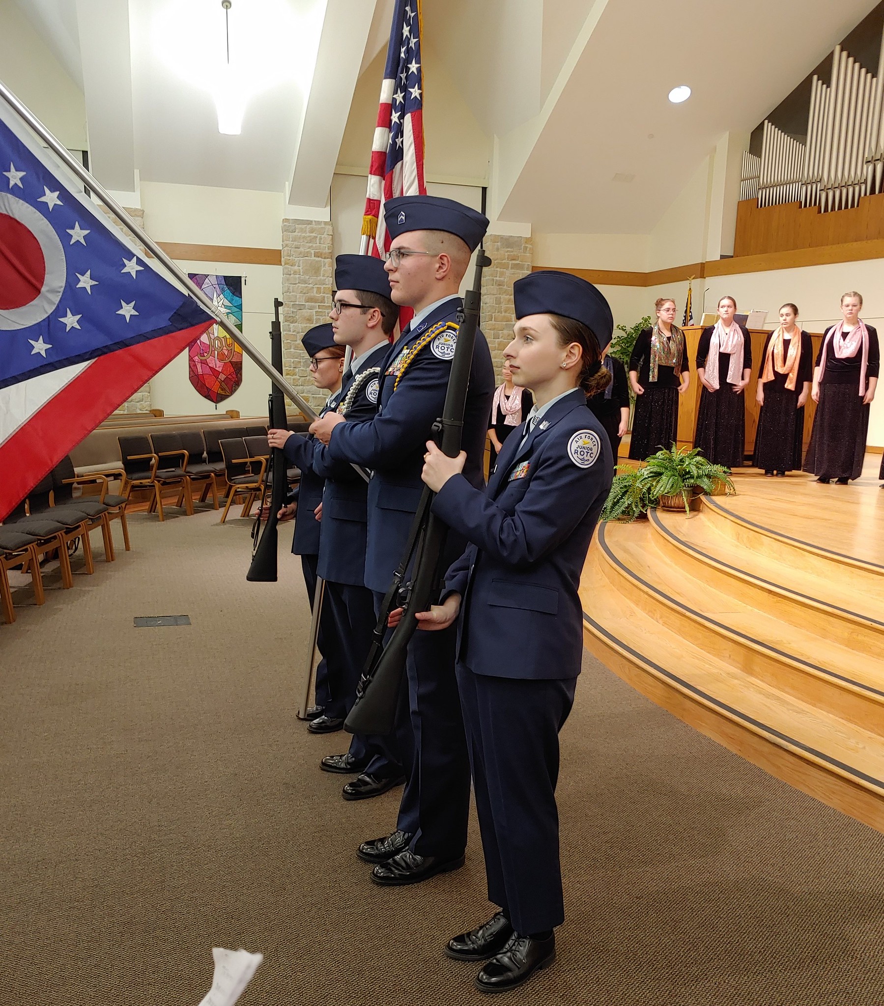 Young people in uniform holding flags as part of a ceremony.