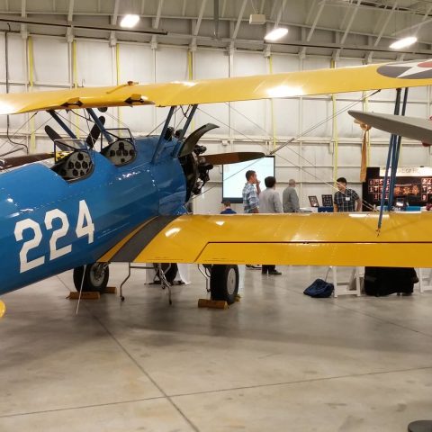 A group of students inside an airplane hanger for an event.