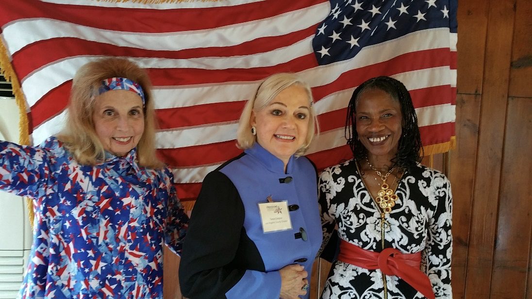 Three adults holding an American Flag behind them at Freedoms Foundation Conference