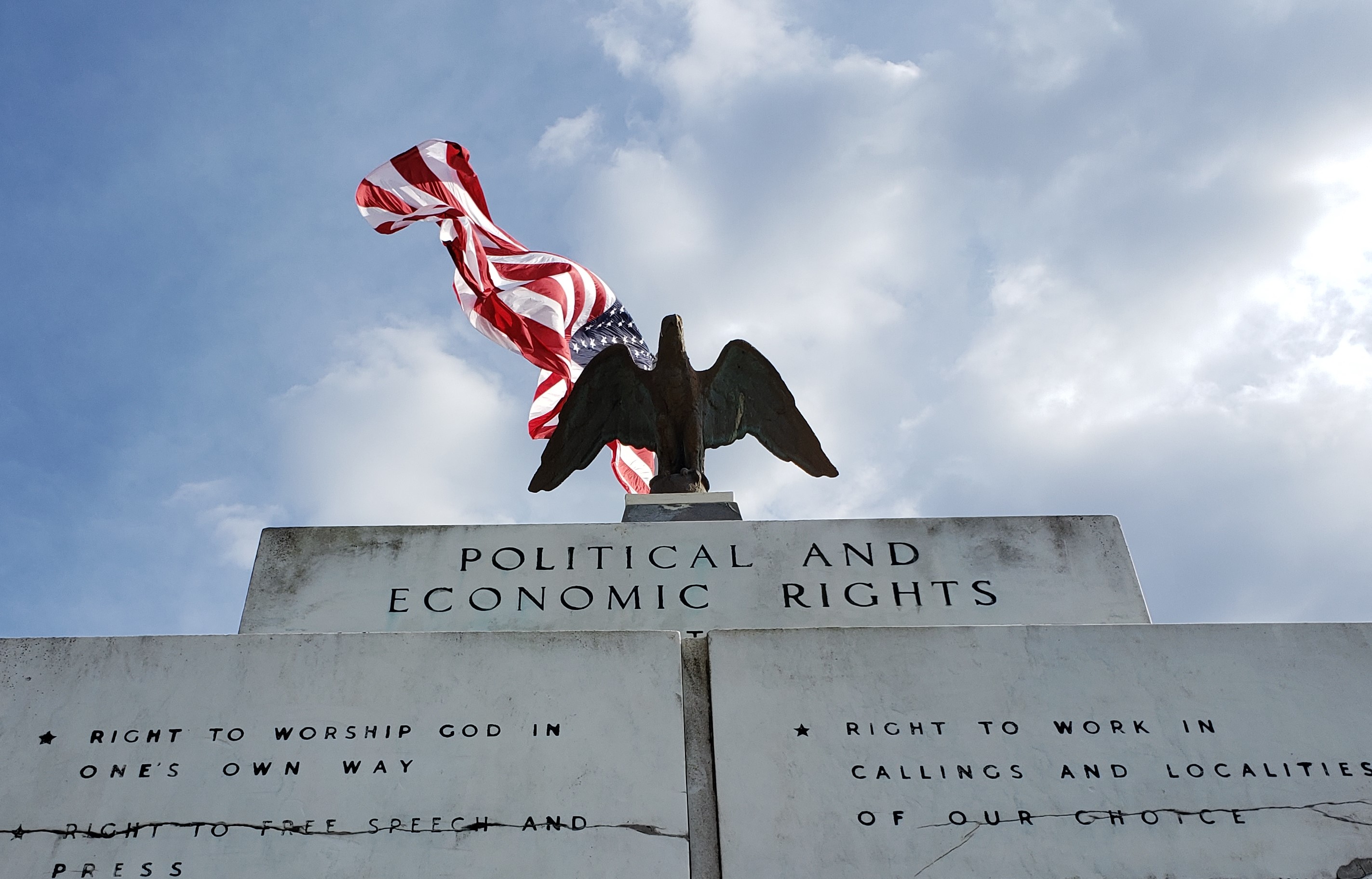 Eagle statue and American Flag above political and economic rights stone wall