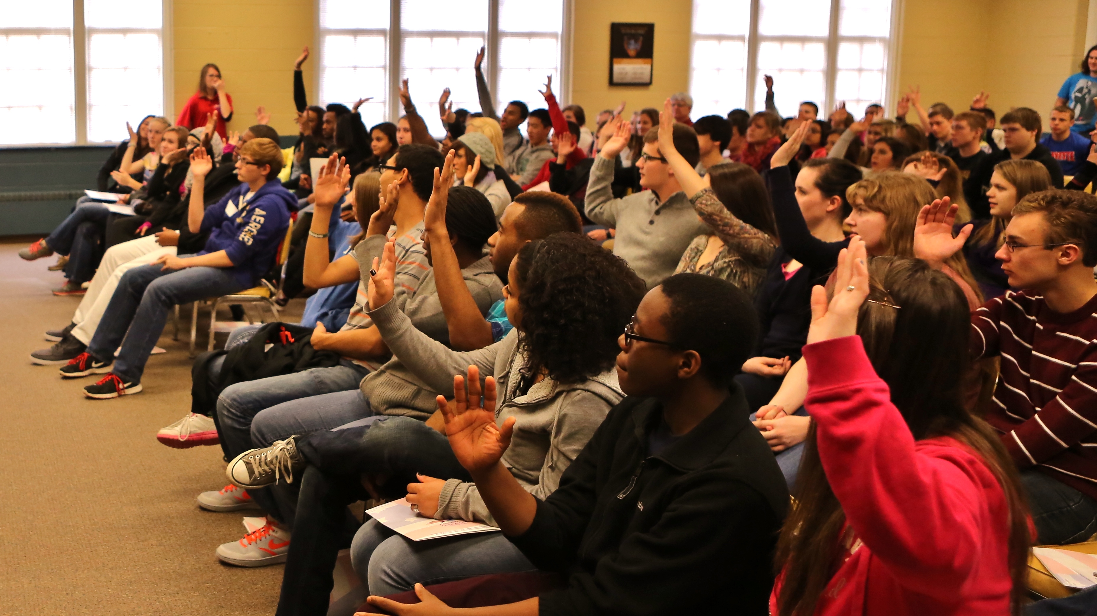 A room full of students attending Spirit of America program, raising their hand to participate.