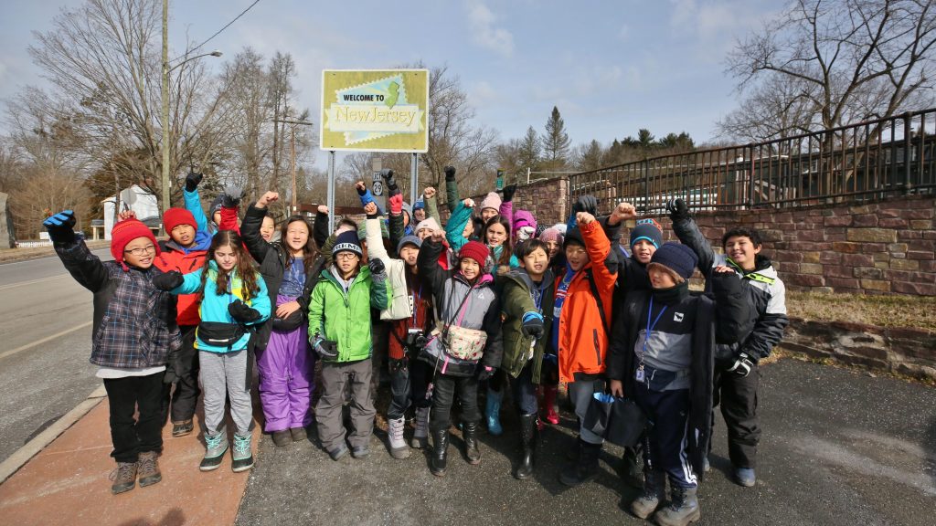 Group of primary school students pose at New Jersey state sign