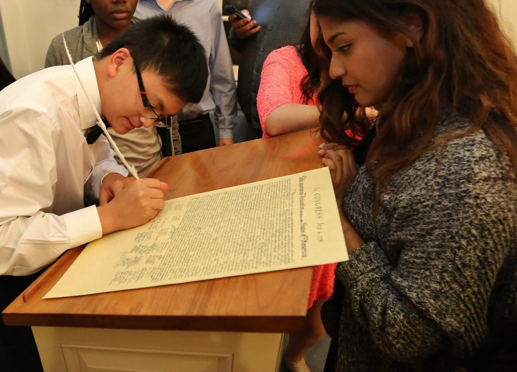 Student signing paper Declaration of Independence in signer's ceremony