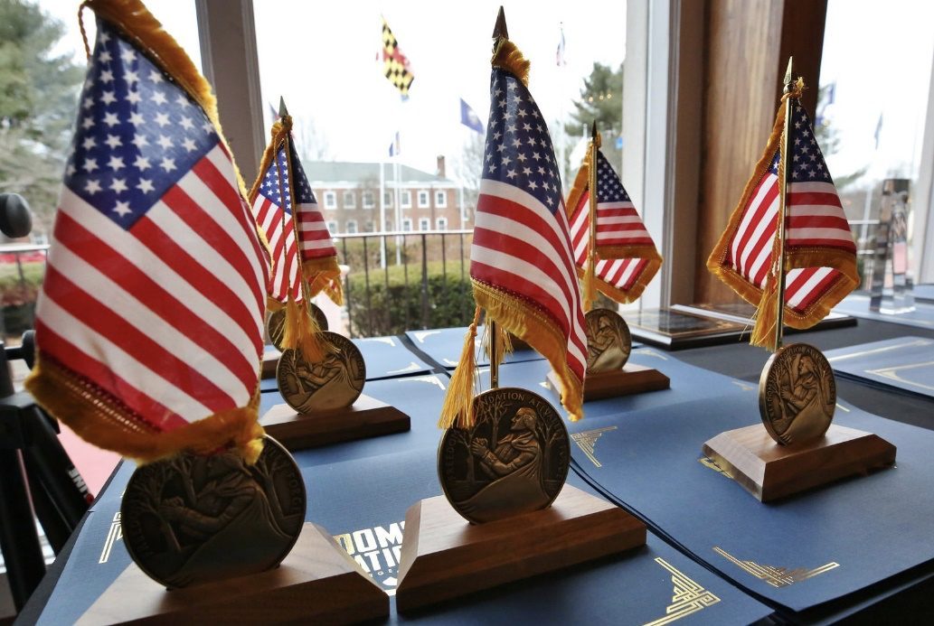 Youth Essay Awards on Table in front of window with American Flags on them