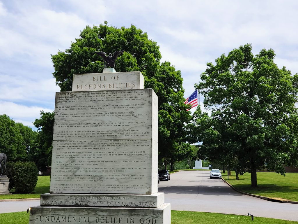 The Bill of Responsibilities Monument on the Valley Forge campus with American flag in the background