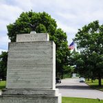 The Bill of Responsibilities Monument on the Valley Forge campus with American flag in the background
