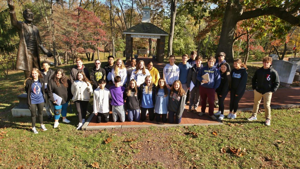 Students picture in front of Medal of Honor Grove Valley Forge.