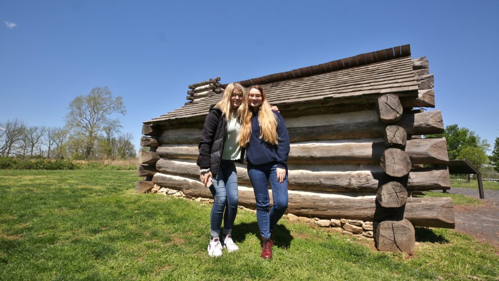 Students posing infront of log cabin at Valley Forge